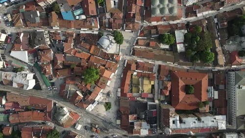 Drone view from above of roofed houses and mosques of Bosnian city, vehicles pass through the street