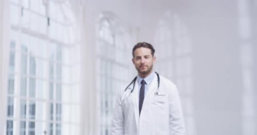 4k video of a young male doctor standing in a hospital