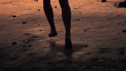 Un homme court en silhouette sur une plage de sable au coucher du soleil au super ralenti