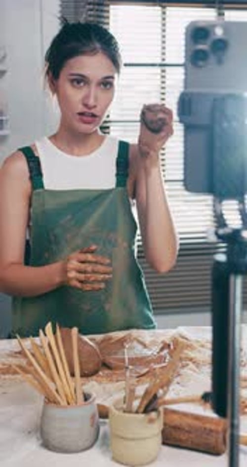 A female ceramicist is teaching about pottery in the workshop online.