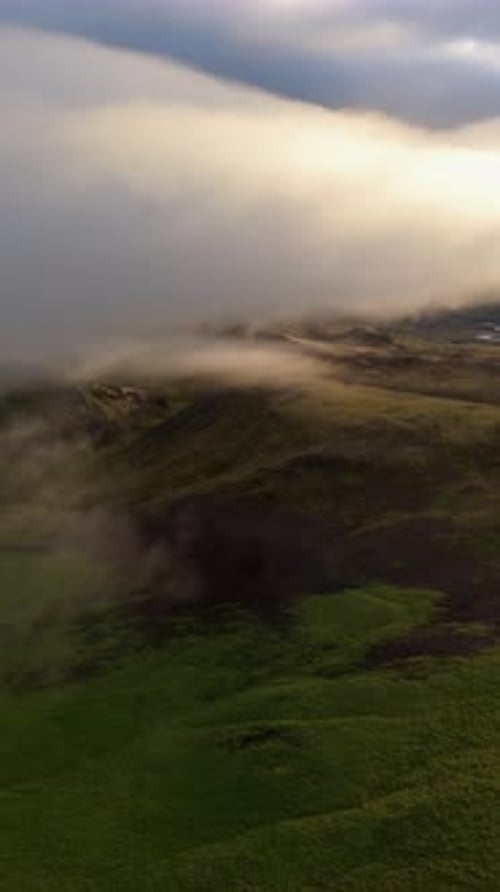 Dramatic Aerial Shot of Mist Enveloping the Lush Terrain of Iceland During Sunrise
