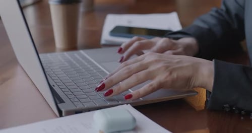 Closeup of Female Hands Typing with Laptop Keyboard Using Computer at Desk in Office