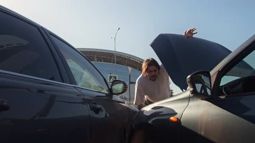 Man Inspecting Car After Accident on City Street
