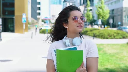 Close Up Portrait of Caucasian Pretty Happy Female Student Holding Notebooks in Hands Walking