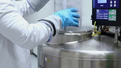 Laboratory technician handling cryogenic storage tank in scientific research facility