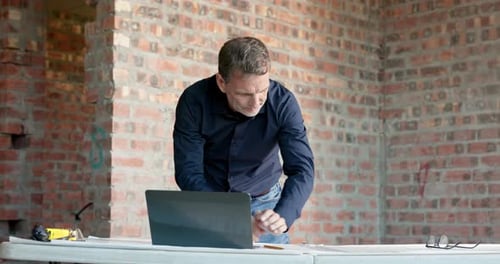Laptop, man and writing on construction site for blueprint correction, drawing update or renovation