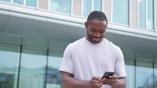 African American Man Holding Smartphone Touch Screen Typing Scroll Page on Urban Street in City Guy