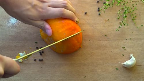 Top down view of male hands cutting orange pumpkin in slice on wooden cutting board