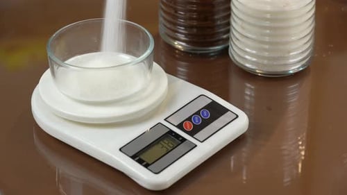 Sucre sur balance. Peser le sucre sur une balance de cuisine.