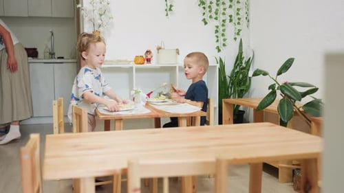 Two Young Boys Eating at a Wooden Table
