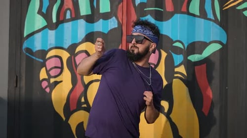 Young Man Dances in Front of Graffiti Art