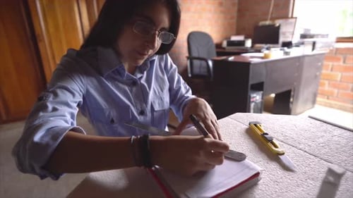 Ingenieurin arbeitet mit Zeichnungen in einem hellen Büro. Architekt Student zeichnet Linien auf Plan