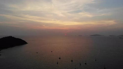 Sunset over the ocean with boats and mountains in the background