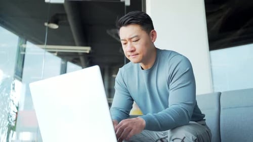 Young exhausted, overworked office worker sitting in the workplace with a severe headache massaging