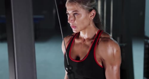 Athletic Woman Bodybuilder Doing Exercises in the Gym
