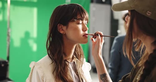 Makeup, lipstick and cosmetologist with woman in studio for photoshoot, filming or production