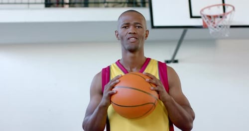 African American man holds a basketball in a gym