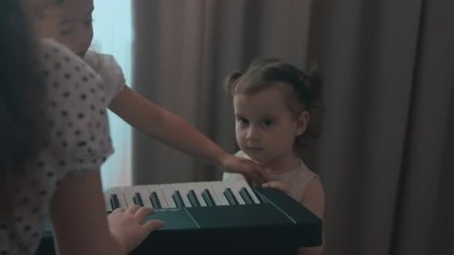 Child and Adult Playing Piano Together Indoors