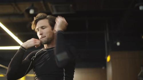 Serious sport man warming up elbows and making box movements at the gym
