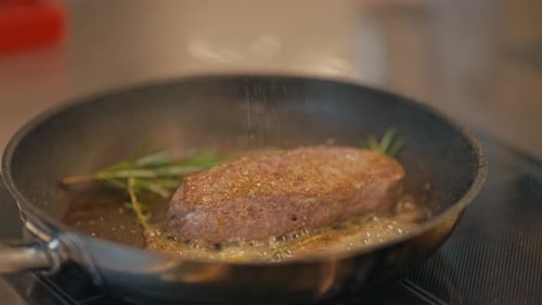 Chef seasoning delicious steak in hot pan, close up view
