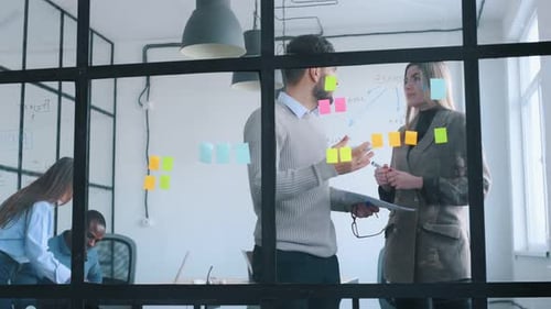 Bunch of stickers on the glass. Professional workers are in the modern office together.