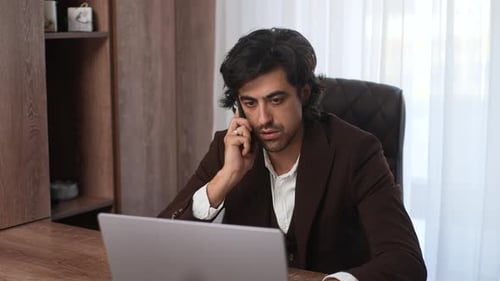 Confident Busy Businessman Talking Smartphone Typing Laptop Multitask in Office Desk Looking to
