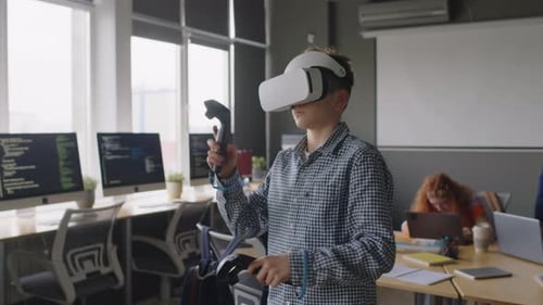Teenage Boy in VR Headset, with Controllers Testing Fight Game at Coding Club