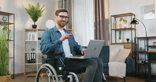 Man in Wheelchair Using Laptop at Home