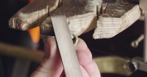 Makro eines Goldschmieds, der den Stahl schneidet und feilt, um einen Ring herzustellen. Konzept: Silber, Stil, Produkte