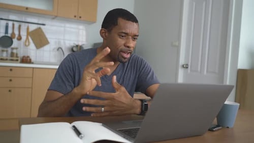 Man Talking on Laptop in Kitchen at Home