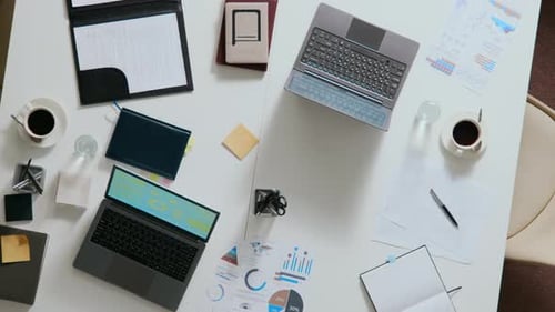 Top Down of Two White Work Desks Put Together Featuring Laptops, Business Papers
