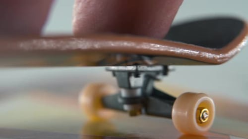 A hyper close-up detailed shot of a mini skateboard, tiny white wheels, riding fingerboard from righ