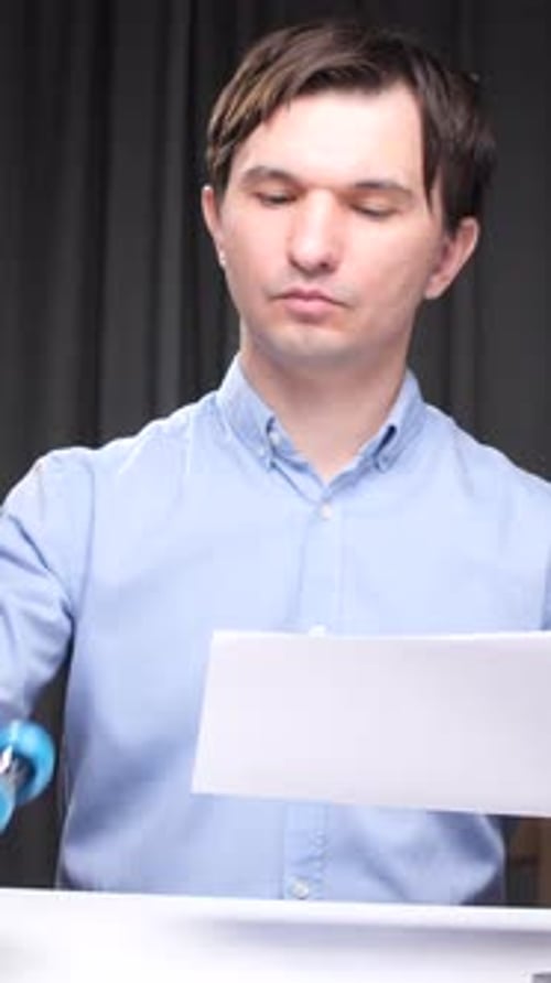 Vertical Video Office Worker Stapling Papers at Desk with Laptop and Folders