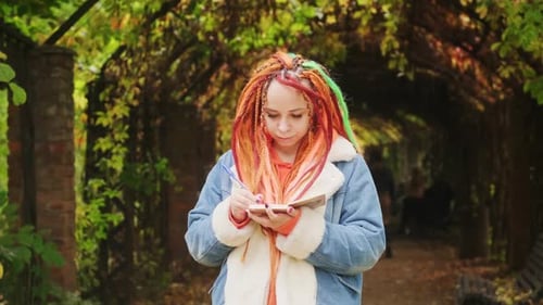 Portrait of Young Woman with Dreadlocks Drawing Writing in Notebook Standing in Archway with