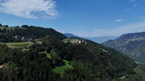 Camera panning over green hills revealing mountain village