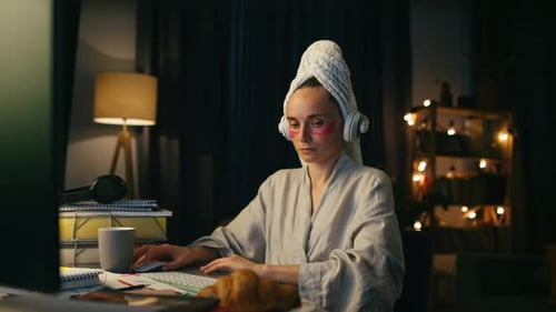 Woman in robe using computer at night at home