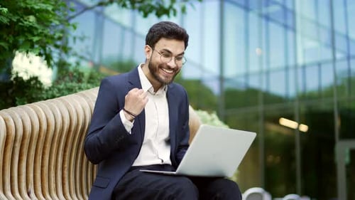 Excited Young Man Working on Laptop Outdoors