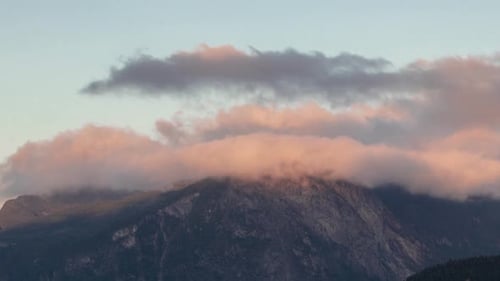 Time-lapse of clouds rolling over majestic mountain range at sunrise sunset
