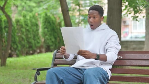Excited Man Celebrating Good News on Park Bench