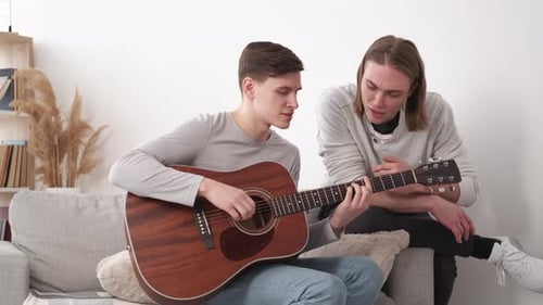 Man Playing Guitar With Friend Giving Advice