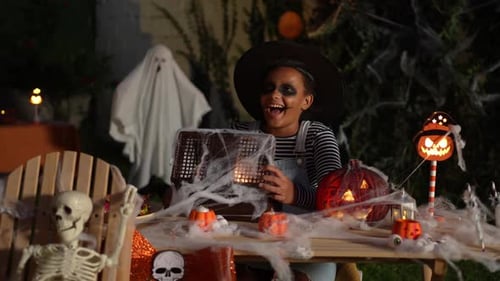 Girl in Witch Costume Looks at Halloween Decoration