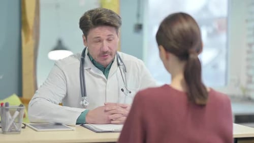 Male Doctor Talking with Patient in Clinic