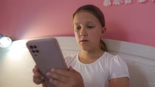 Young Girl in Bed Looking at Phone