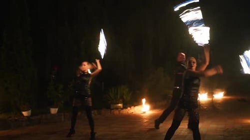 Dynamic Fire Performers Manipulating Flames at Night