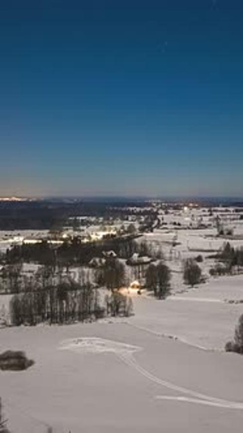 Stunning Nighttime Motion Aerial Over Snowy Rural Landscape with Stars