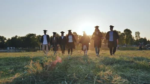 College Graduates Walk at Sunset Holding Hands