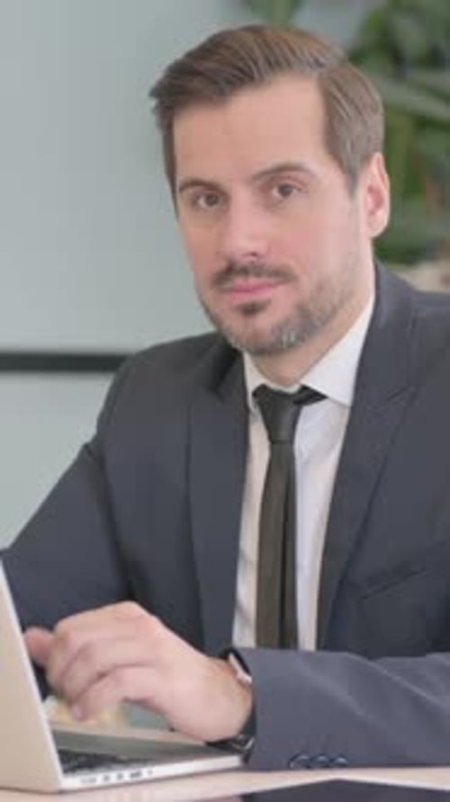 Man in Suit Working at Laptop Gives Thumbs Up