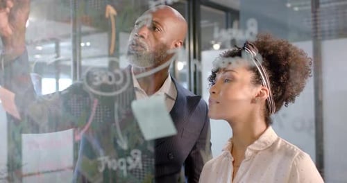 African american businessman writing on glass wall in office with copy space