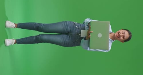 Asian Woman Using Laptop Computer And Smiling To Camera On Green Screen Background In The Studio
