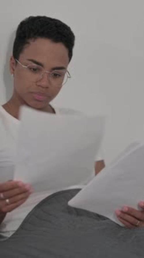 African Woman Reading Documents while Sitting in Bed, Vertical Video